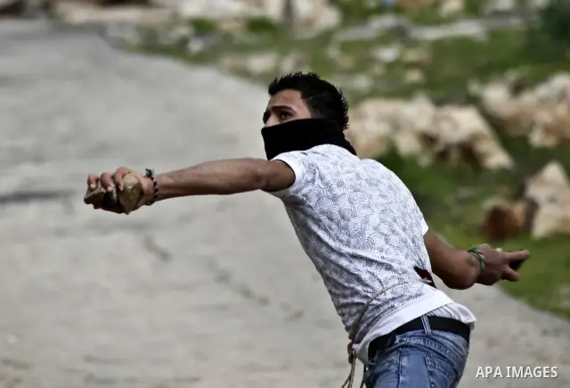 Palestinian youth hurls stones during a protest against the controversial Israeli barrier in the West Bank village of Bilin near Ramallah, Feb. 25, 2011. Photo by Issam Rimawi