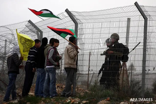 Israeli soldiers take position as Palestinians hold national flag during a protest against the controversial Israeli barrier in the West Bank village of Bilin near Ramallah, Feb. 25, 2011. Photo by Issam Rimawi