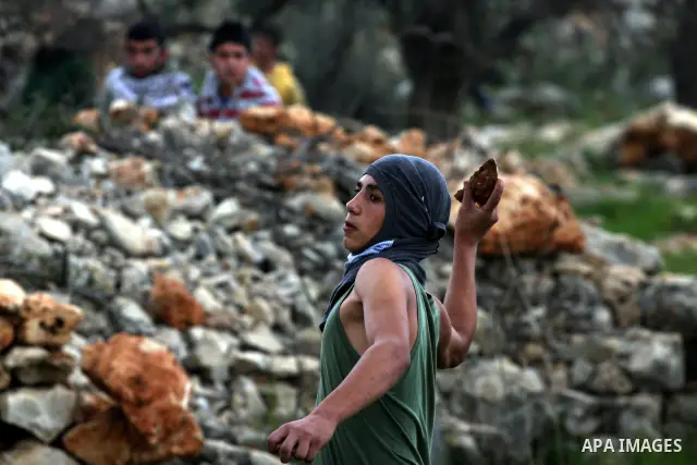 Palestinian youth hurls stones during a protest against the controversial Israeli barrier in the West Bank village of Bilin near Ramallah, Feb. 25, 2011. Photo by Issam Rimawi
