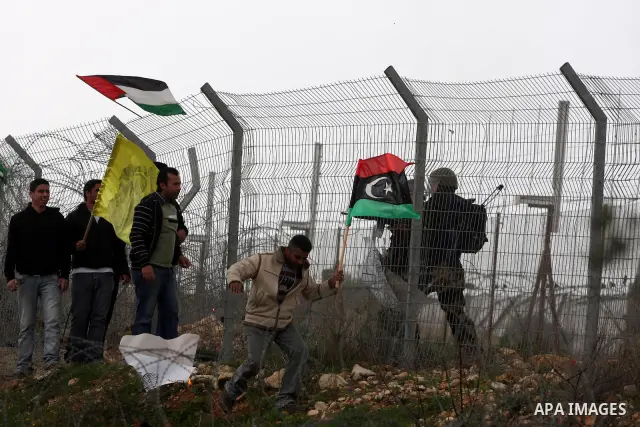 Israeli soldiers take position as Palestinians hold national flag during a protest against the controversial Israeli barrier in the West Bank village of Bilin near Ramallah, Feb. 25, 2011. Photo by Issam Rimawi