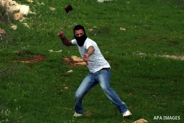 Palestinian youth hurls stones during a protest against the controversial Israeli barrier in the West Bank village of Bilin near Ramallah, Feb. 25, 2011. Photo by Issam Rimawi