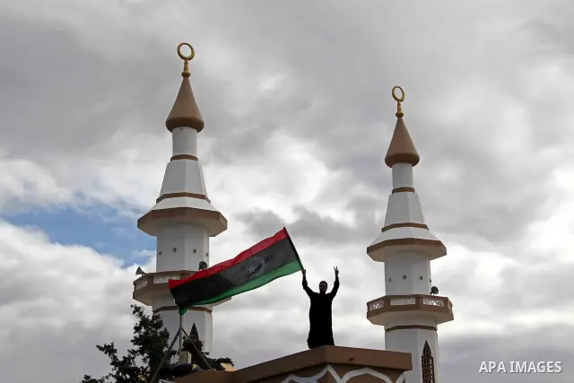 Libyan protester holds the national flag during a rally against Libyan leader Moammar Gadhafi at the Court Square in Derna, Libya, on Feb. 25, 2011. Photo by Karam Nasser