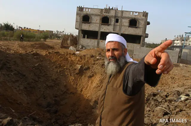 A Palestinian man stands next to a crater left after a missile fired from an Israeli warplane hit Nusairat refugee camp, Central Gaza strip, Saturday, Feb. 26, 2011. The Israeli airforce attacked Friday night several tar...