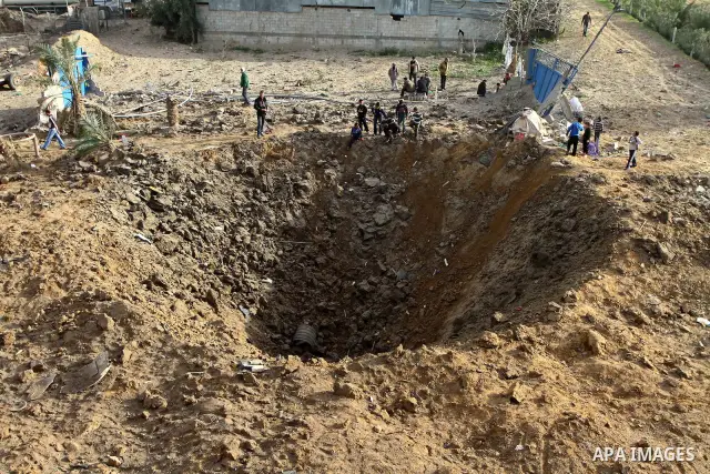 Palestinians stand next to a crater left after a missile fired from an Israeli warplane hit Nusairat refugee camp, Central Gaza strip, Saturday, Feb. 26, 2011. The Israeli airforce attacked Friday night several targets i...