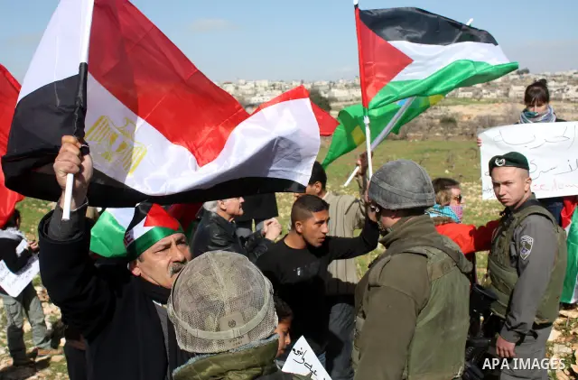 Israeli soldiers stand guard during a demonstration by Palestinian, Israeli and foreign activists against the demolishing of farm land to be used in the construction of Jewish settlements near the existing Israeli settle...