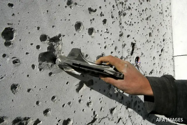 A Palestinian man carries shrapnel that hit house by Israeli artillery, in the southern Gaza strip town of Rafah on February 28, 2011. A Palestinian laborer was injured who was collecting gravel near the airport, while t...