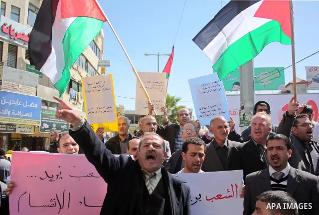 Palestinian protestors hold national flags and banners during a rally against the U.S. veto and calling for the national reconciliation, in the West Bank city of Hebron, on March 03, 2011. Photo by Najeh Hashlamoun