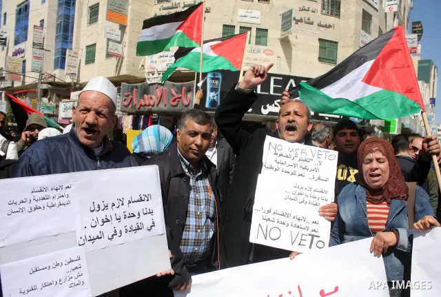 Palestinian protestors hold national flags and banners during a rally against the U.S. veto and calling for the national reconciliation, in the West Bank city of Hebron, on March 03, 2011. Photo by Najeh Hashlamoun