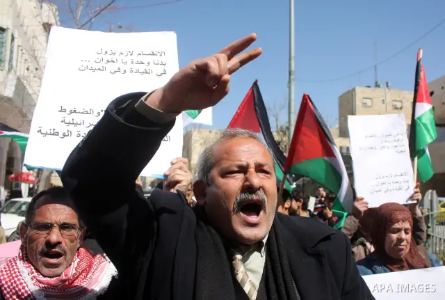 Palestinian protestors hold national flags and banners during a rally against the U.S. veto and calling for the national reconciliation, in the West Bank city of Hebron, on March 03, 2011. Photo by Najeh Hashlamoun