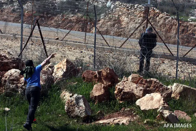 A Palestinian youth hurls a stone at Israeli soldiers during a protest against Israel's controversial separation barrier in the village of Bilin, near the West Bank city of Ramallah, in the Israeli occupied West Bank, on...