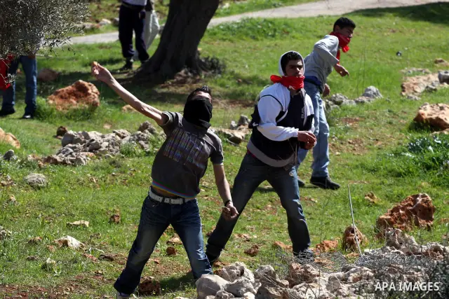 A Palestinian youth hurls a stone at Israeli soldiers during a protest against Israel's controversial separation barrier in the village of Bilin, near the West Bank city of Ramallah, in the Israeli occupied West Bank, on...