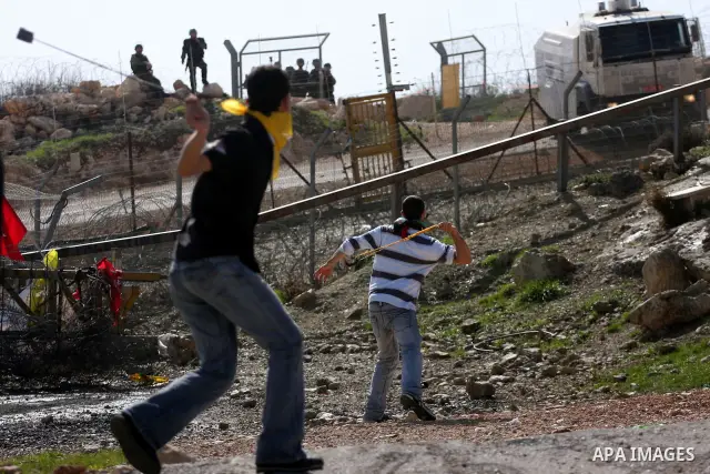 A Palestinian youth hurls a stone at Israeli soldiers during a protest against Israel's controversial separation barrier in the village of Bilin, near the West Bank city of Ramallah, in the Israeli occupied West Bank, on...