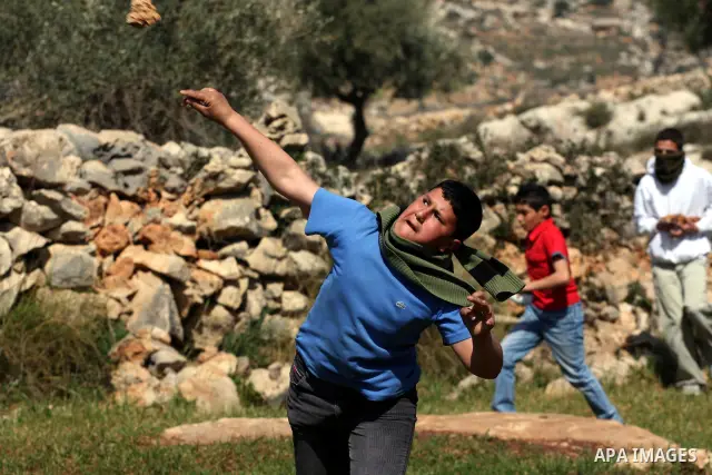 A Palestinian youth hurls a stone at Israeli soldiers during a protest against Israel's controversial separation barrier in the village of Bilin, near the West Bank city of Ramallah, in the Israeli occupied West Bank, on...