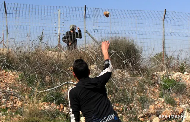 A Palestinian demonstrator hurls stones at Israeli troops during a protest against the construction of Israel's separation barrier in the West Bank village of Bilin near Ramallah, Friday,March 4, 2011. Photo by Wagdi Esh...