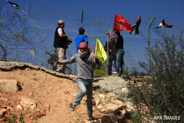 Palestinian demonstrators holds Palestinian flags during a protestagainst the construction of Israel's separation barrier in the West Bank village of Bilin near Ramallah, Friday,March 4, 2011. Photo by Wagdi Eshtayah