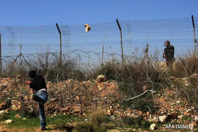 A Palestinian demonstrator hurls stones at Israeli troops during a protest against the construction of Israel's separation barrier in the West Bank village of Bilin near Ramallah, Friday,March 4, 2011. Photo by Wagdi Esh...