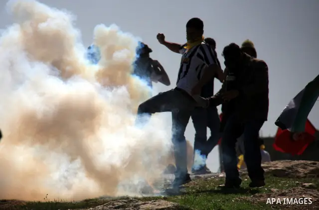 Palestinians, Israelis and foreign demonstrators run from tear gas fired by Israeli troops during a protest against the construction of Israel's separation barrier in the West Bank village of Bilin near Ramallah, Friday,...