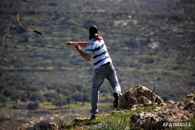 A Palestinian demonstrator uses a sling-shot to hurl stones at Israeli troops during a protest against the construction of Israel's separation barrier in the West Bank village of Bilin near Ramallah, Friday,March 4, 2011...