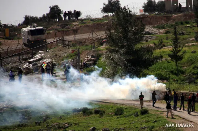 Palestinians, Israelis and foreign demonstrators run from tear gas fired by Israeli troops during a protest against the construction of Israel's separation barrier in the West Bank village of Bilin near Ramallah, Friday,...