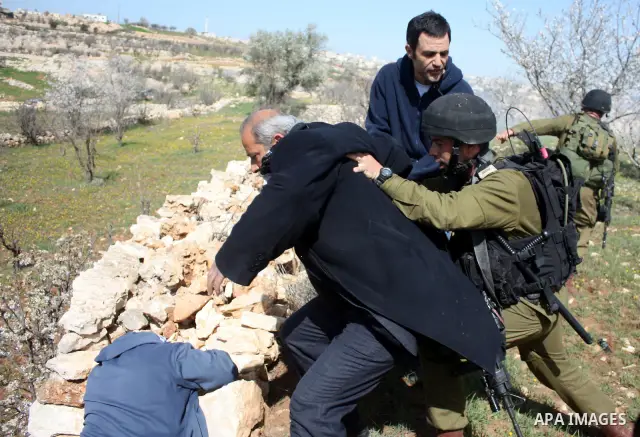 Israeli soldiers throw a stun grenade and fire tear gas towards Palestinian ,Israelian and International protesters during a demonstration against the demolishing of farm land to be used in the construction of Jewish set...