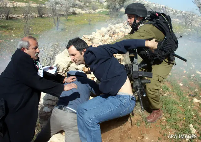 Israeli soldiers throw a stun grenade and fire tear gas towards Palestinian ,Israelian and International protesters during a demonstration against the demolishing of farm land to be used in the construction of Jewish set...