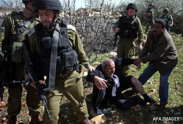 Israeli soldiers throw a stun grenade and fire tear gas towards Palestinian ,Israelian and International protesters during a demonstration against the demolishing of farm land to be used in the construction of Jewish set...