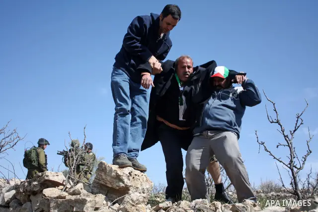 A Palestinian man receives help during a demonstration by Palestinian ,Israeli and International protesters against the demolishing of farm land to be used in the construction of Jewish settlements near the existing Isra...