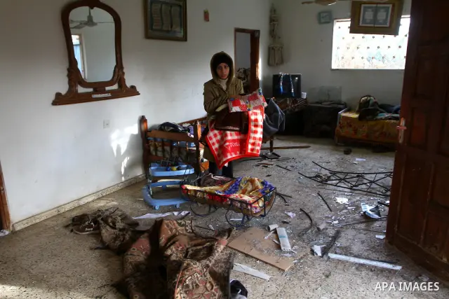 A Palestinian woman inspects the damage in her house following an Israeli airstrike in Deir al-Balah refugee camp, southern Gaza Strip, Sunday, March 6, 2011. Photo by Ashraf Amra