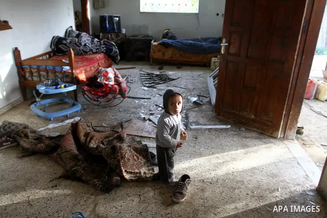 A Palestinian boy plays near the damage in his house following an Israeli airstrike in Deir al-Balah refugee camp, southern Gaza Strip, Sunday, March 6, 2011. Photo by Ashraf Amra