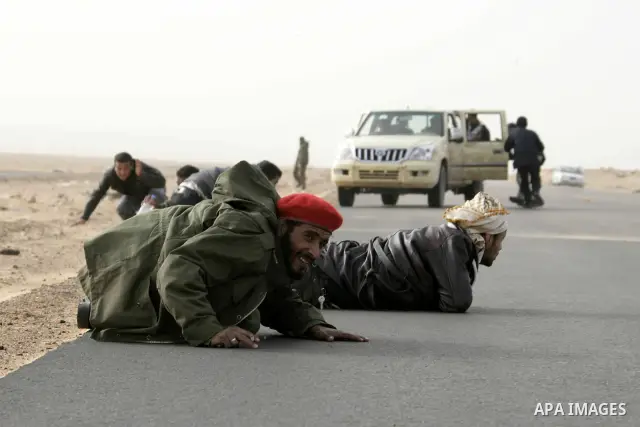 Rebel fighters take cover from shelling by soldiers loyal to Libyan leader Muammar Gaddafi during a battle near Ras Lanuf, March 4, 2011. Heavily armed rebels clashed with forces loyal to Gaddafi on Friday on the outskir...
