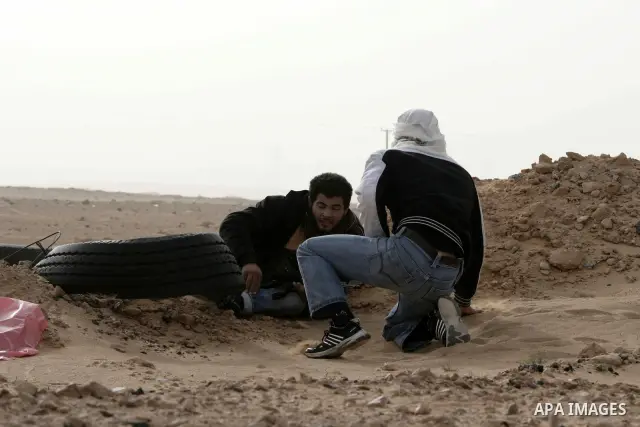 Rebel fighters take cover from shelling by soldiers loyal to Libyan leader Muammar Gaddafi during a battle near Ras Lanuf, March 4, 2011. Heavily armed rebels clashed with forces loyal to Gaddafi on Friday on the outskir...