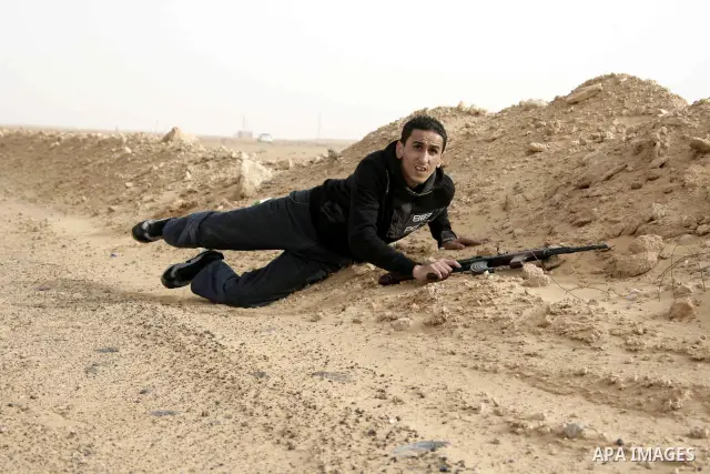 Rebel fighters take cover from shelling by soldiers loyal to Libyan leader Muammar Gaddafi during a battle near Ras Lanuf, March 4, 2011. Heavily armed rebels clashed with forces loyal to Gaddafi on Friday on the outskir...
