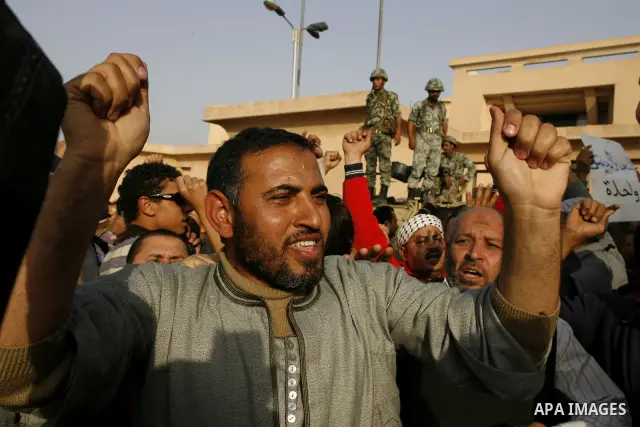 Egyptian protesters chant slogans during a demonstration in front of an Egyptian state security building in the outskirts of Cairo on Mach 5, 2011 while state security employees briefly fired gunshots as hundreds of prot...
