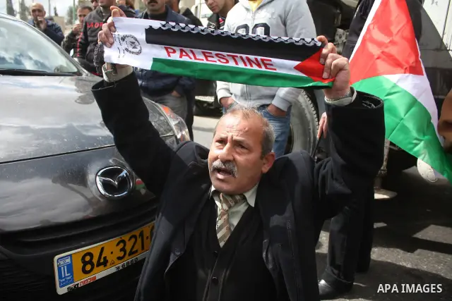 Palestinian men wave their national flag as they sit and block Road 60, which links Jerusalem and Hebron and is used by both Palestinians and Jewish settlers, on March 08,2011 in Beit Omar near the West Bank city of Hebr...