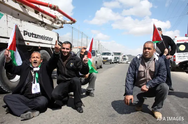 Palestinian men wave their national flag as they sit and block Road 60, which links Jerusalem and Hebron and is used by both Palestinians and Jewish settlers, on March 08,2011 in Beit Omar near the West Bank city of Hebr...