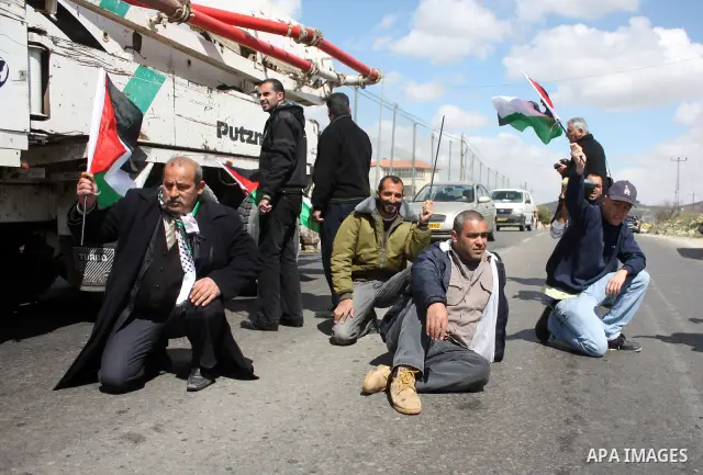 Palestinian men wave their national flag as they sit and block Road 60, which links Jerusalem and Hebron and is used by both Palestinians and Jewish settlers, on March 08,2011 in Beit Omar near the West Bank city of Hebr...