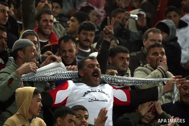 Palestinian fans watch their national football team play against Thailand during their qualifier for the Asian group of the 2012 London Olympics on March 9, 2011 at the Faisal Husseini stadium in the West Bank town of al...