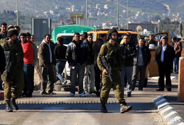 Israeli soldiers check identity cards of Palestinians at a military checkpoint of Hawara near the West Bank city of Nablus on March 12, 2011. The Israeli army announced the Palestinian city as closed military zone follow...