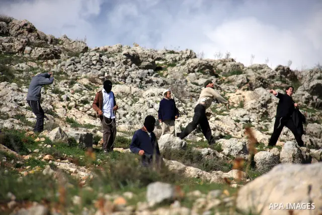 Israeli settlers from the Bracha settlement throw stones at Palestinian youth in the West Bank village of Burin on March 12, 2011 during clashes after an overnight attack in which five members of an Israeli family were k...