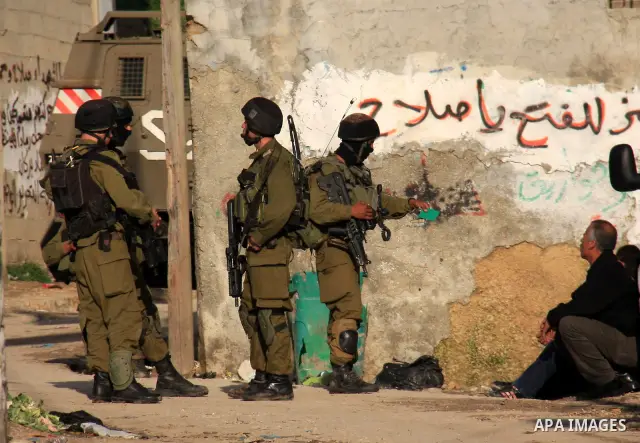 Israeli soldiers take position at Awarta Village south of the West Bank city of Nablus during a search operation on 12 March ,2011. The Israeli army announced the Palestinian city as closed military zone following the ki...
