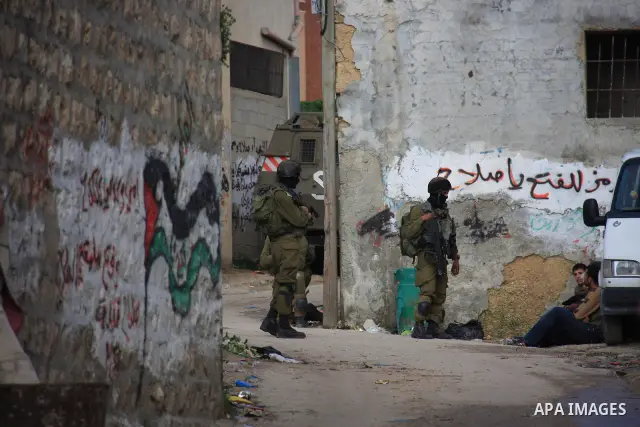 Israeli soldiers take position at Awarta Village south of the West Bank city of Nablus during a search operation on 12 March ,2011. The Israeli army announced the Palestinian city as closed military zone following the ki...