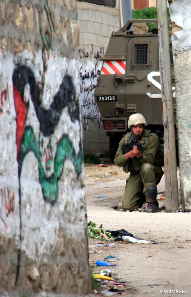 Israeli soldiers take position at Awarta Village south of the West Bank city of Nablus during a search operation on 12 March ,2011. The Israeli army announced the Palestinian city as closed military zone following the ki...