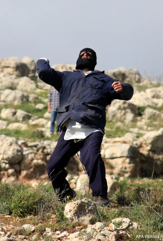 Israeli settlers from the Bracha settlement throw stones at Palestinian youth in the West Bank village of Burin on March 12, 2011 during clashes after an overnight attack in which five members of an Israeli family were k...