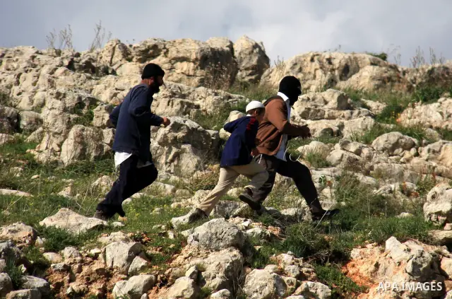 Israeli settlers from the Bracha settlement throw stones at Palestinian youth in the West Bank village of Burin on March 12, 2011 during clashes after an overnight attack in which five members of an Israeli family were k...