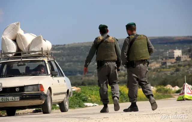 An Israeli soldier stops Palestinians for a security check in the West Bank village of Awarta south of Nablus on 13 March 2011. Israeli troops raided the village, arresting people and searching houses a day after a Pales...