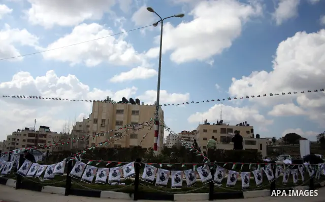 Palestinians hang banners in the West Bank city of Ramallah with pictures of Fatah member Dalal Mughrabi, who led an attack on an Israeli bus near Tel Aviv, killing 36 people in 1978, on the 32nd anniversary of the attac...