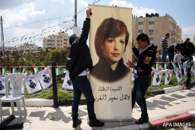 Palestinians hang banners in the West Bank city of Ramallah with pictures of Fatah member Dalal Mughrabi, who led an attack on an Israeli bus near Tel Aviv, killing 36 people in 1978, on the 32nd anniversary of the attac...