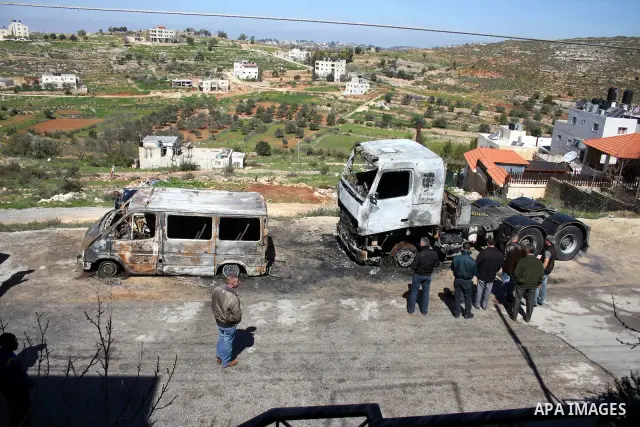 Palestinians stand next to vehicles they said were set on fire by Jewish settlers in retaliation following a deadly attack on a settler family on Friday, in the West Bank in Ramallah, Monday, March 14, 2011. The U.S. Emb...
