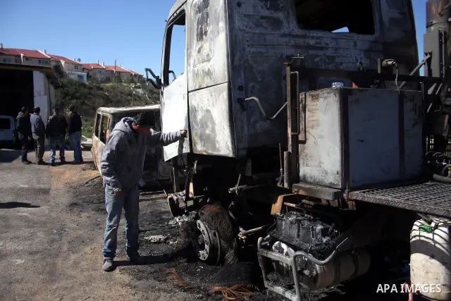 Palestinians stand next to vehicles they said were set on fire by Jewish settlers in retaliation following a deadly attack on a settler family on Friday, in the West Bank in Ramallah, Monday, March 14, 2011. The U.S. Emb...