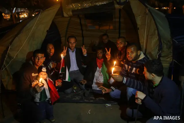 Palestinian demonstrators hold candles and placards as they prepare to spend the night on the street during a rally in Gaza City, calling for an end to Palestinian divisions March 14, 2011. Some 500 Palestinians, answeri...